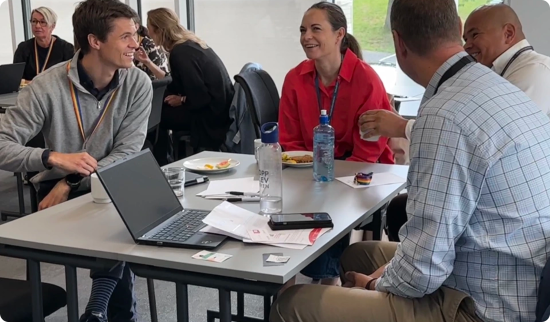 Gruppe mennesker som ler og prater sammen rundt et bord